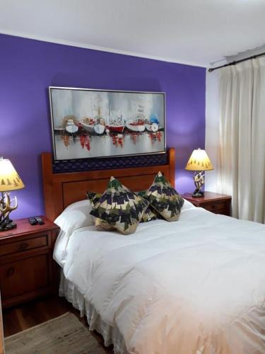 a bedroom with a large white bed with two lamps at DEPARTAMENTOS TERMAS DE CHILLAN in Nevados de Chillan