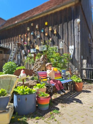 a child sitting on a bench in a garden at Romantische Wohnung Bauernhof, 100m2 offenes Dachgeschoss in Auhausen