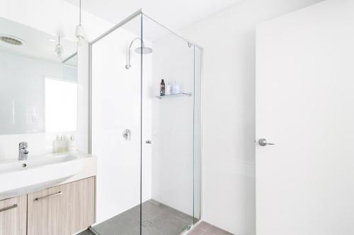 a white bathroom with a shower and a sink at Beautiful Modern 3 Bedroom Family Suite Sleeps 6 in Brisbane