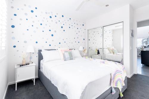 Beautiful Modern 3 Bedroom Family Suite Sleeps 6 في بريزبين: غرفة نوم بيضاء مع سرير كبير ومرآة