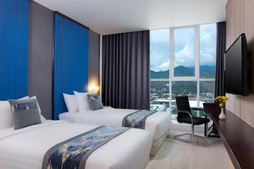 a hotel room with two beds and a window at Horison Ultima Entrop Papua in Jayapura