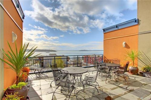 a patio with tables and chairs on a balcony at DT Designer's 2BR Condo Parking Tub Pool - 99 walk score in Seattle