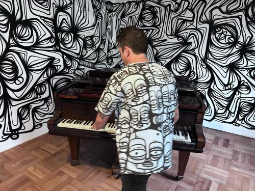 Un uomo che suona un pianoforte davanti a un muro di Art Apartment a Santiago