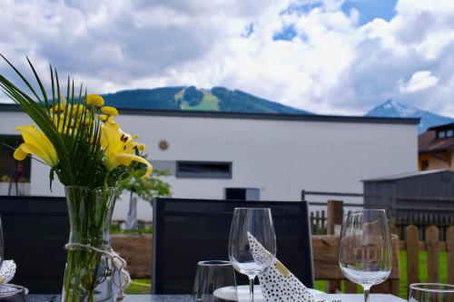a table with two wine glasses and a vase with flowers at Appartement Ausblick in Radstadt