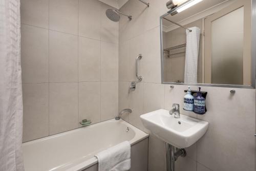 a bathroom with a sink and a tub and a mirror at City Limits Hotel Apartments in Melbourne