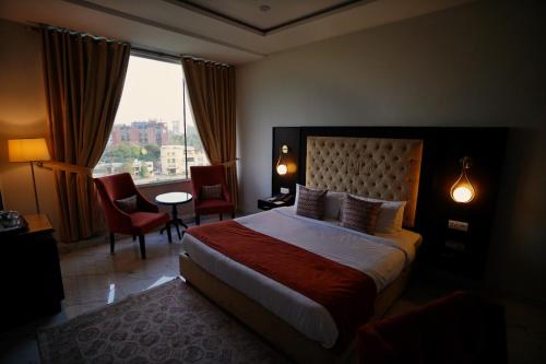 Faletti’s Grand MM Alam Road في لاهور: غرفة فندقية بسرير كبير ونافذة