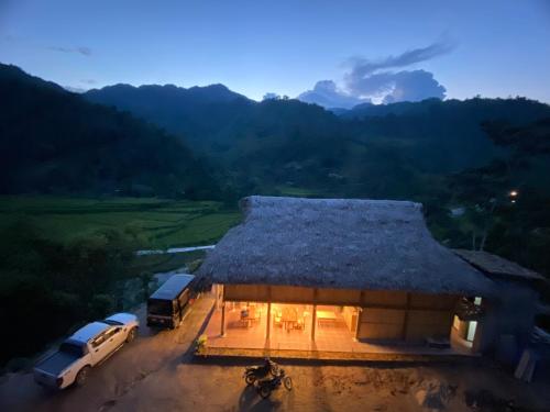 a building with a grass roof with cars parked in front at Tay Eco House in Nam Vong