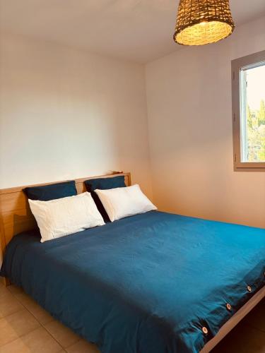une chambre avec un lit bleu et une fenêtre dans l'établissement Mas de la canopée-Luberon, à Saint-Saturnin-lès-Apt