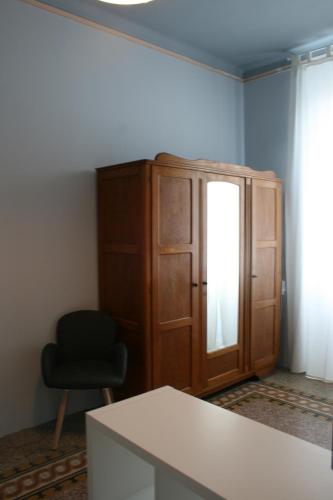 Habitación con armario de madera y silla negra. en sauro 56 camera azzurra, en La Spezia