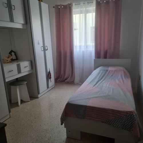 um quarto com uma cama e uma janela com cortinas cor-de-rosa em A room in Luqa em Luqa