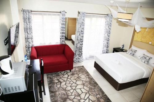 um quarto com uma cama e uma cadeira vermelha em Studio Nairobi Mvuli em Nairobi
