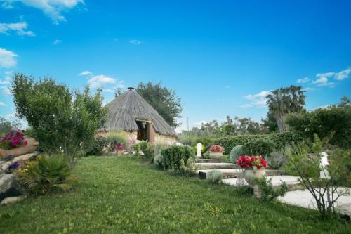 un jardín con techo de paja en La Pinnetta With Pool - Happy Rentals, en Codrongianos