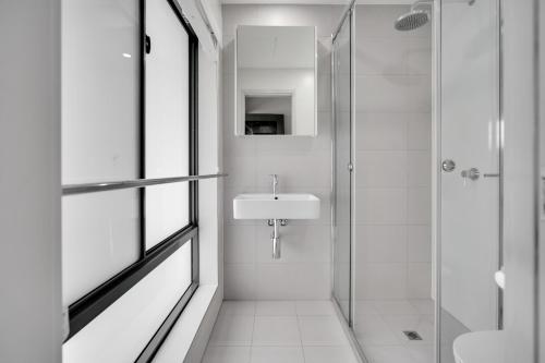 a white bathroom with a sink and a shower at Belmoral Corporate Suites in Townsville