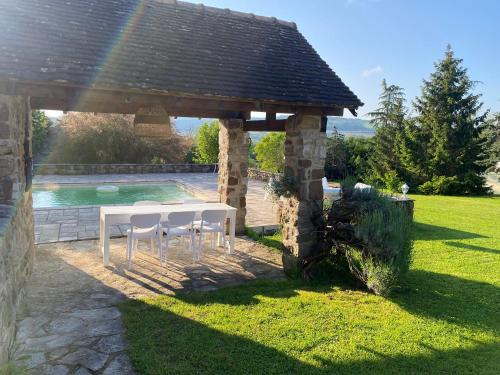 einen Tisch und Stühle unter einem Pavillon neben einem Pool in der Unterkunft gite seccotine in Saint-Mard-de-Vaux