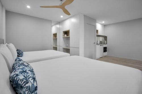 a white bedroom with a bed and a ceiling fan at Belmoral Corporate Suites in Townsville