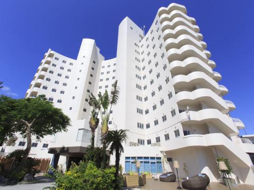 twee witte gebouwen met palmbomen voor hen bij TWIN LINE HOTEL YANBARU OKINAWA JAPAN Formerly Okinawa Suncoast Hotel in Nago