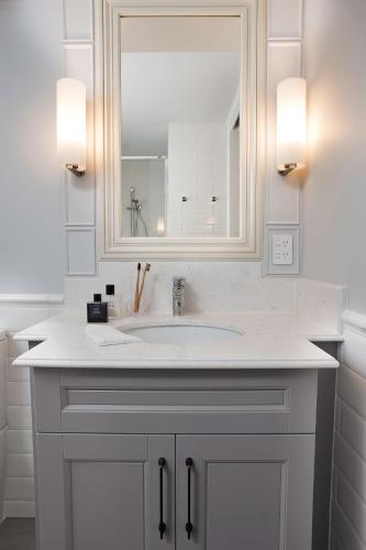 a white bathroom with a sink and a mirror at The Arbour Boutique Apartments in Toowoomba