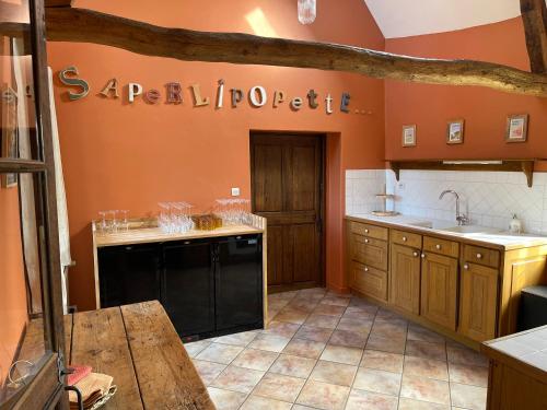 une cuisine avec des murs orange et un lave-vaisselle noir dans l'établissement Saperlipopette charmante demeure en pierre de taille, à Baincthun