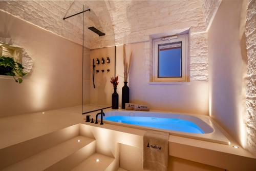 La salle de bains est pourvue d'une baignoire et d'une fenêtre. dans l'établissement Naiira Luxury Trullo, à Alberobello