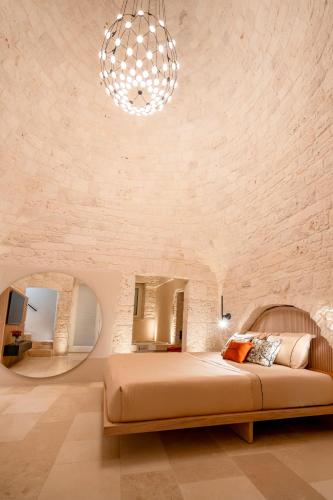 a bedroom with a large bed and a chandelier at Naiira Luxury Trullo - jacuzzi and patio in Alberobello