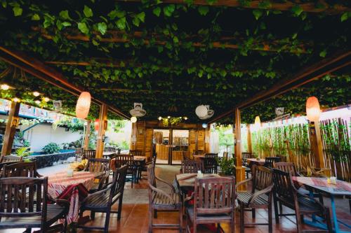 un restaurante con mesas, sillas y plantas en Chanthavong Hostel en Luang Prabang