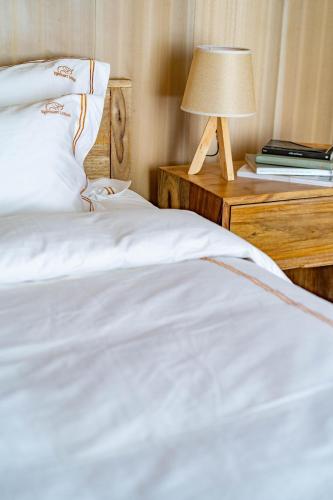 a bed with white sheets and a table with a lamp at Elephant lodge in Kwa Kuchinia