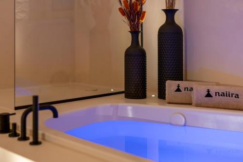 a bath tub with two black vases at Naiira Luxury Trullo - jacuzzi and patio in Alberobello