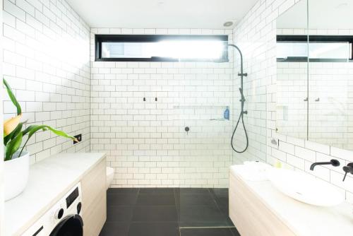 ein weißes Bad mit einem Waschbecken und einer Dusche in der Unterkunft Green Door Gem - Your Stylish Retreat in South Melbourne in Melbourne