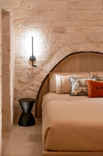 a bedroom with a large bed with a stone wall at Naiira Luxury Trullo - jacuzzi and patio in Alberobello