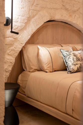 a bed with a wooden headboard and pillows at Naiira Luxury Trullo - jacuzzi and patio in Alberobello