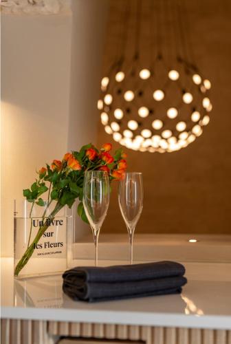 a table with two wine glasses and a vase with flowers at Naiira Luxury Trullo - jacuzzi and patio in Alberobello