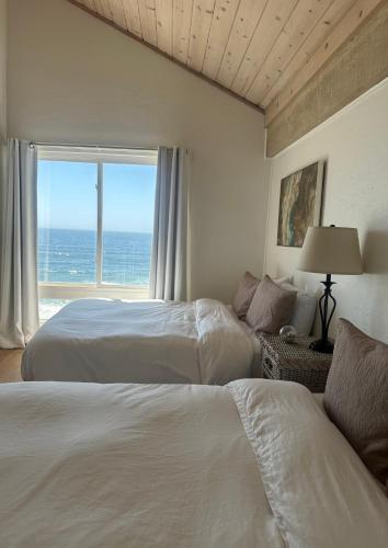 two beds in a room with a view of the ocean at La Selva Beach Ocean Front Townhome - Direct Beach & Ocean Access in La Selva Beach