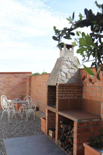 a brick patio with a barbecue with a table and chairs at L'ocell del Pla in Ivars d'Urgell