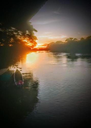 un barco en el agua al atardecer en un río en The Smiling Lao, en Muang Không