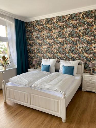 a bedroom with a large white bed with a floral wall at 2-Zimmer Zentral in Ferdinandshof, WLAN Modern in Ferdinandshof