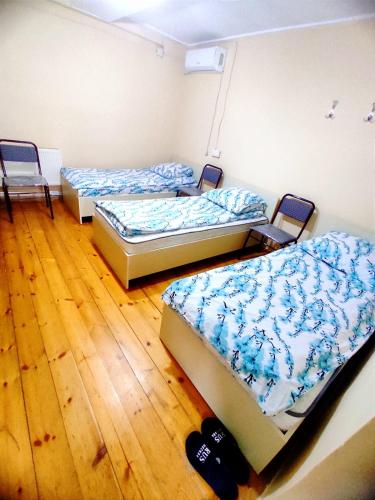 3 camas en una habitación con suelo de madera en Hostel ucuz, en Lankaran