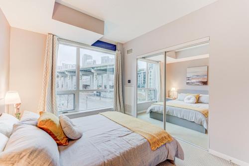 1 Schlafzimmer mit 2 Betten und einem großen Fenster in der Unterkunft Prime City Pad 2 Bedroom with CN Tower View in Toronto