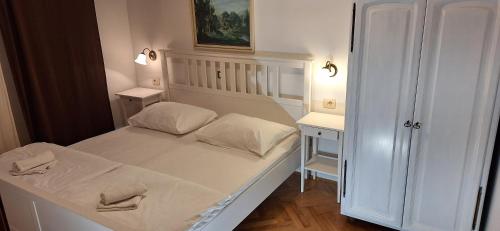 a small bedroom with a white bed and two tables at Summerhouse Duće Omiš in Duće