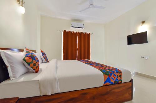 a bedroom with a large white bed and a window at FabHotel Sterling Garden in Old Goa