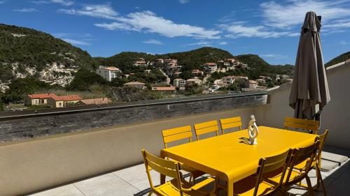 a yellow table and chairs on a balcony with a view at Superbe 3 chambres 150m2 - Parking gratuit, Climatisation, Terrasses - Standing in Bonifacio