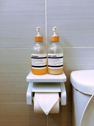 two bottles of cleaning products sitting on a shelf next to a toilet at Muji Homestay Ria Heights Tawau in Tawau