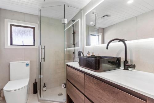 a bathroom with a sink and a toilet at Seaside Serenity 4BR Modern Home in Auckland