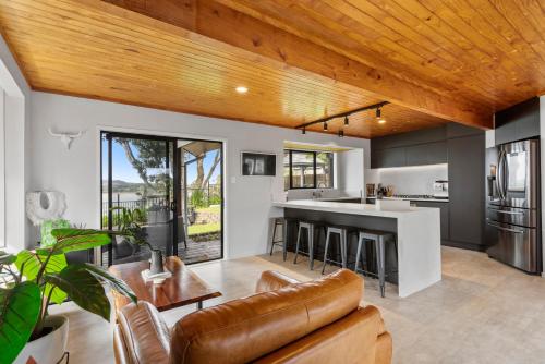 a living room with a couch and a kitchen at Seaside Serenity 4BR Modern Home in Auckland