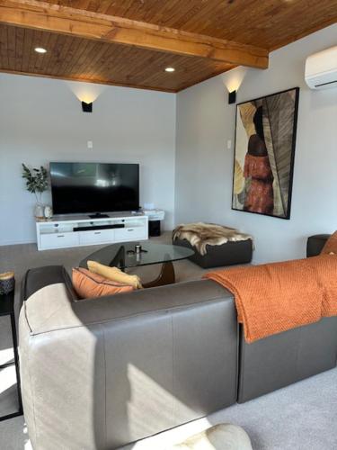 a living room with a couch and a tv at Seaside Serenity 4BR Modern Home in Auckland