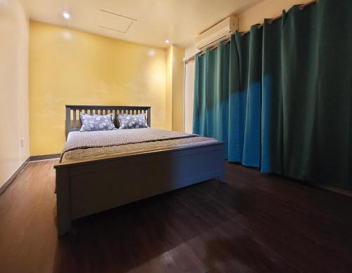 een slaapkamer met een groot bed en blauwe gordijnen bij Sensi Stay in Garapan