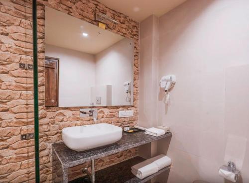 a bathroom with a white sink and a stone wall at Vanya - Urban Villa and Resorts in Belparāo