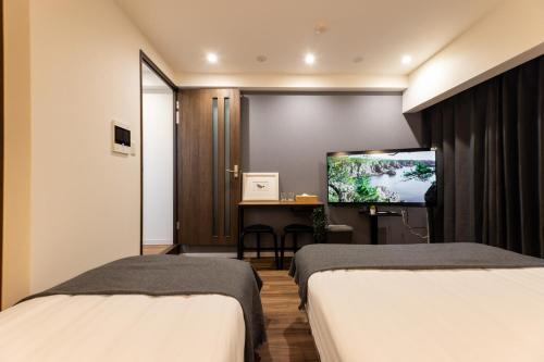 a hotel room with two beds and a flat screen tv at Sanctuary Residence難波大国Ⅱ in Osaka