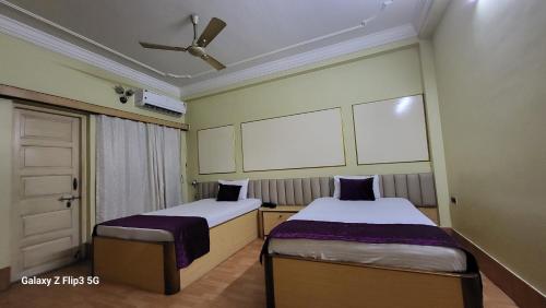 twee bedden in een kleine kamer met een raam bij Hotel Sangam in Baharampur