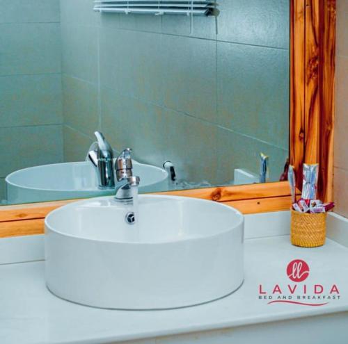bagno con lavandino bianco e specchio di Lavida Inn a Dar es Salaam