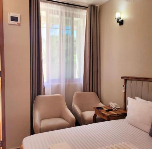 um quarto de hotel com uma cama e duas cadeiras e uma janela em Lavida Inn em Dar es Salaam